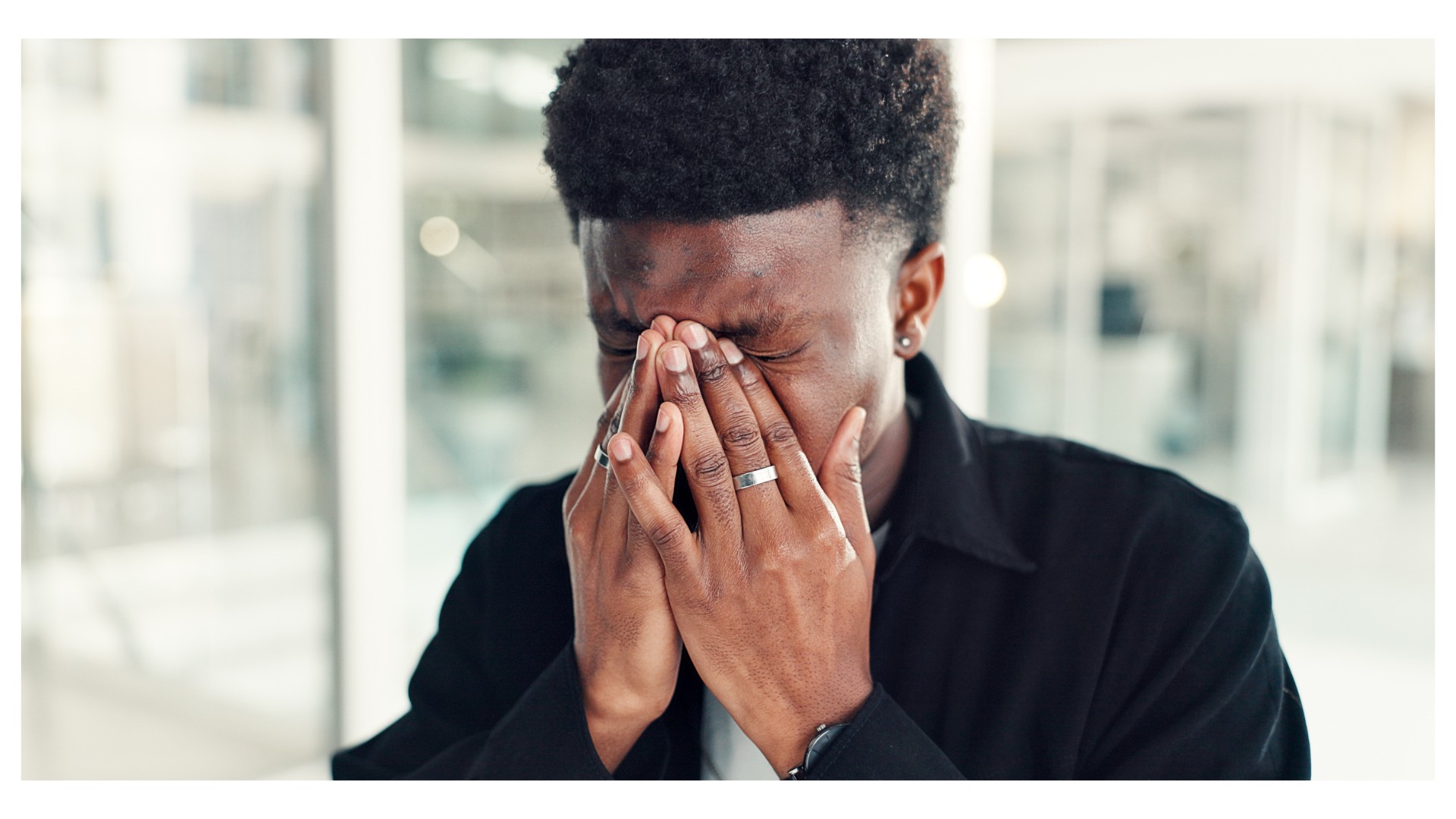 A man pressing his hands to his face in discomfort, representing headache, an early HIV symptom
