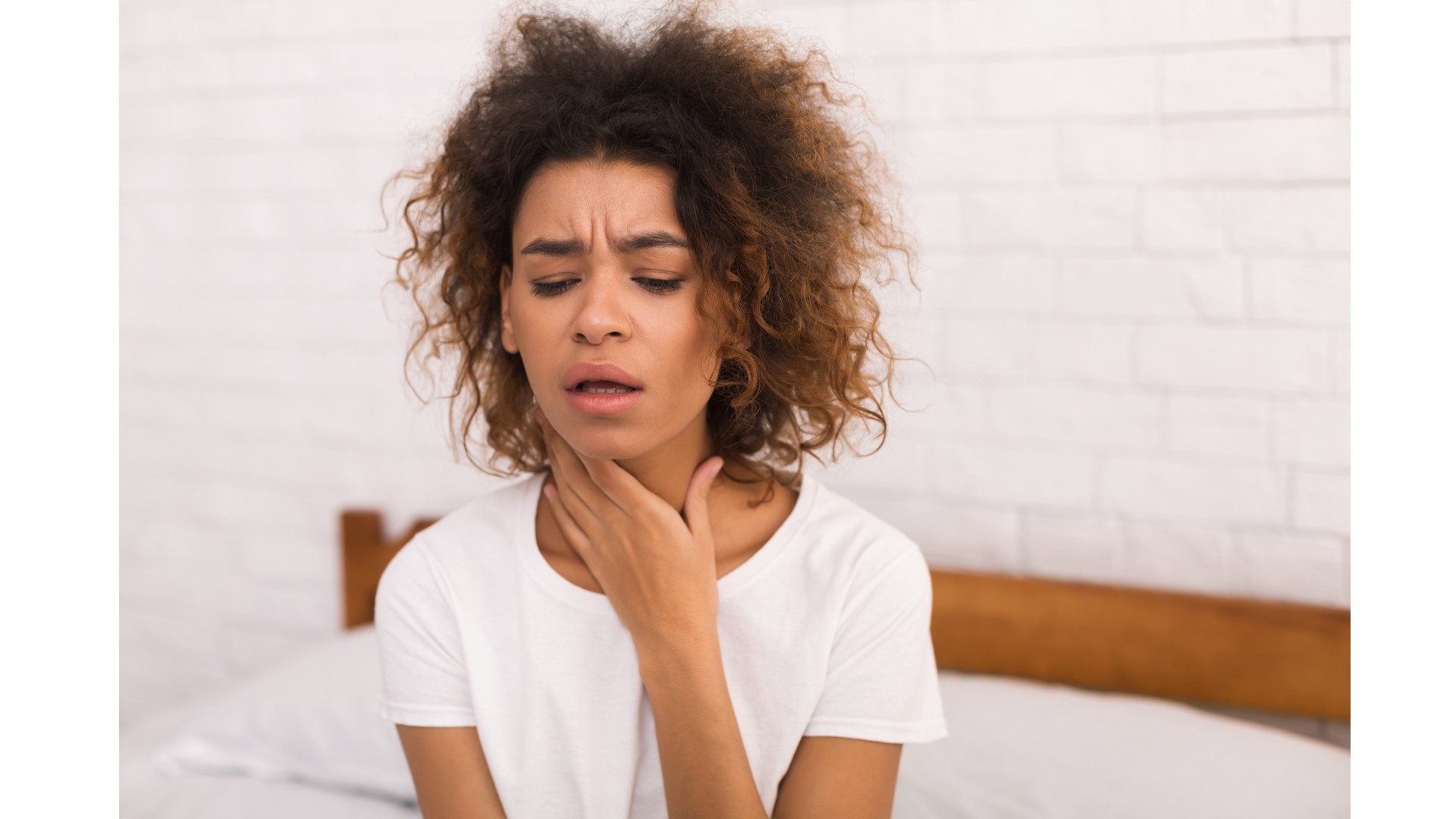 A woman holding her throat in discomfort, representing sore throat, an early HIV symptom