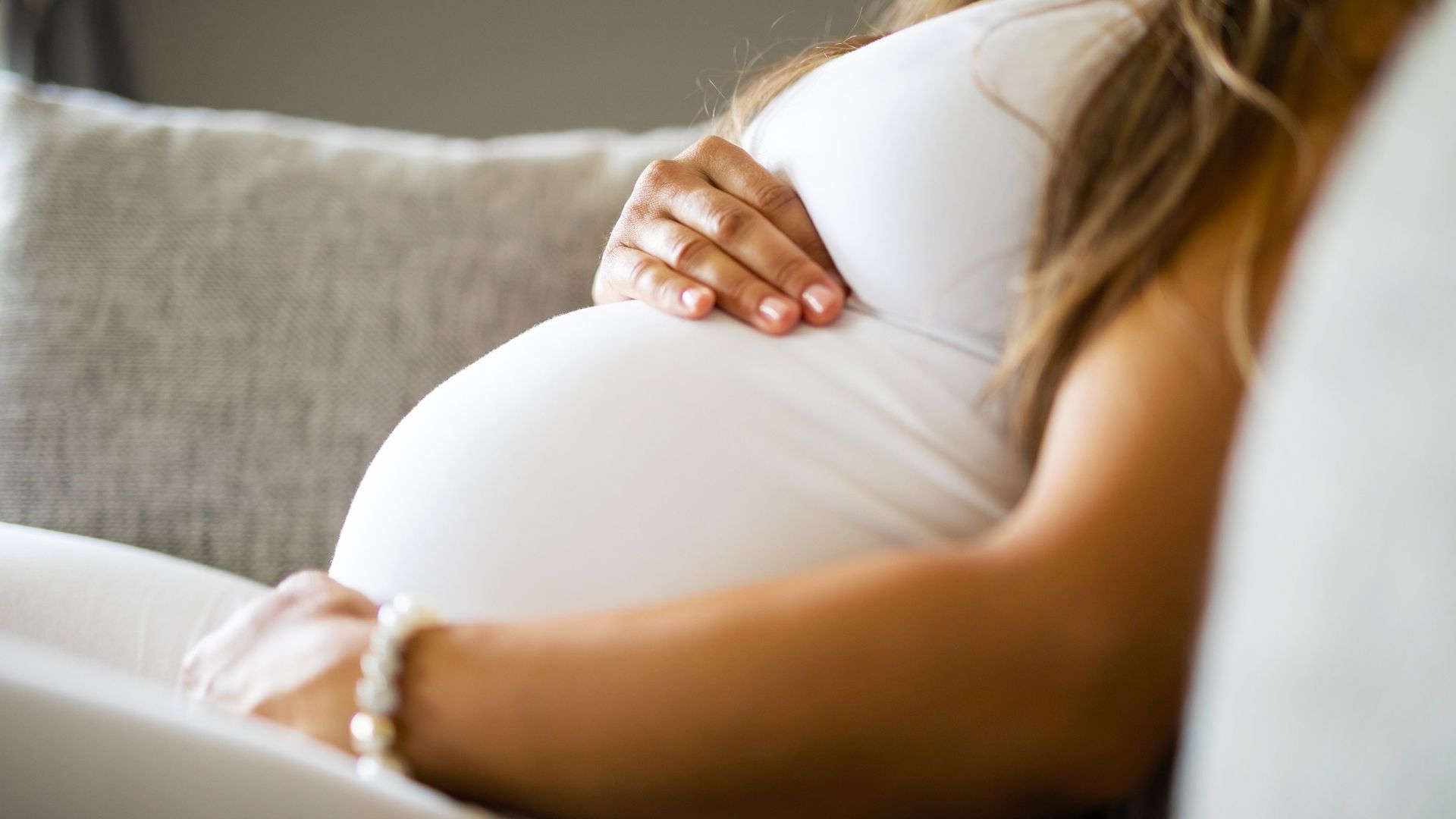 Pregnant woman resting a hand on her stomach, representing the importance of testing during pregnancy